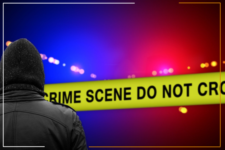 A person wearing a hooded jacket is standing in front of a yellow police tape with the words “CRIME SCENE DO NOT CROSS” prominently displayed. The background features blurred red and blue police lights, suggesting an active investigation scene. This image may be relevant for legal services provided by Miracles Law Group, particularly in criminal defense cases. This image effectively conveys the seriousness of murder or attempted murder cases and highlights the expertise of Miracles Law Group in handling such cases.