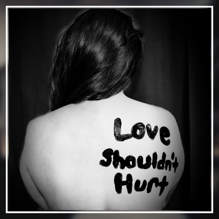 The image appears to depict a collection of Scrabble game tiles scattered on a wooden surface. In the center, the word “JUSTICE” is spelled out with the tiles aligned neatly in a row. Each letter tile also displays a number, which represents the points each letter would score in the game. The letters ‘J’ and ‘C’ have values of 8 and 3 respectively, while other letters are partially obscured.